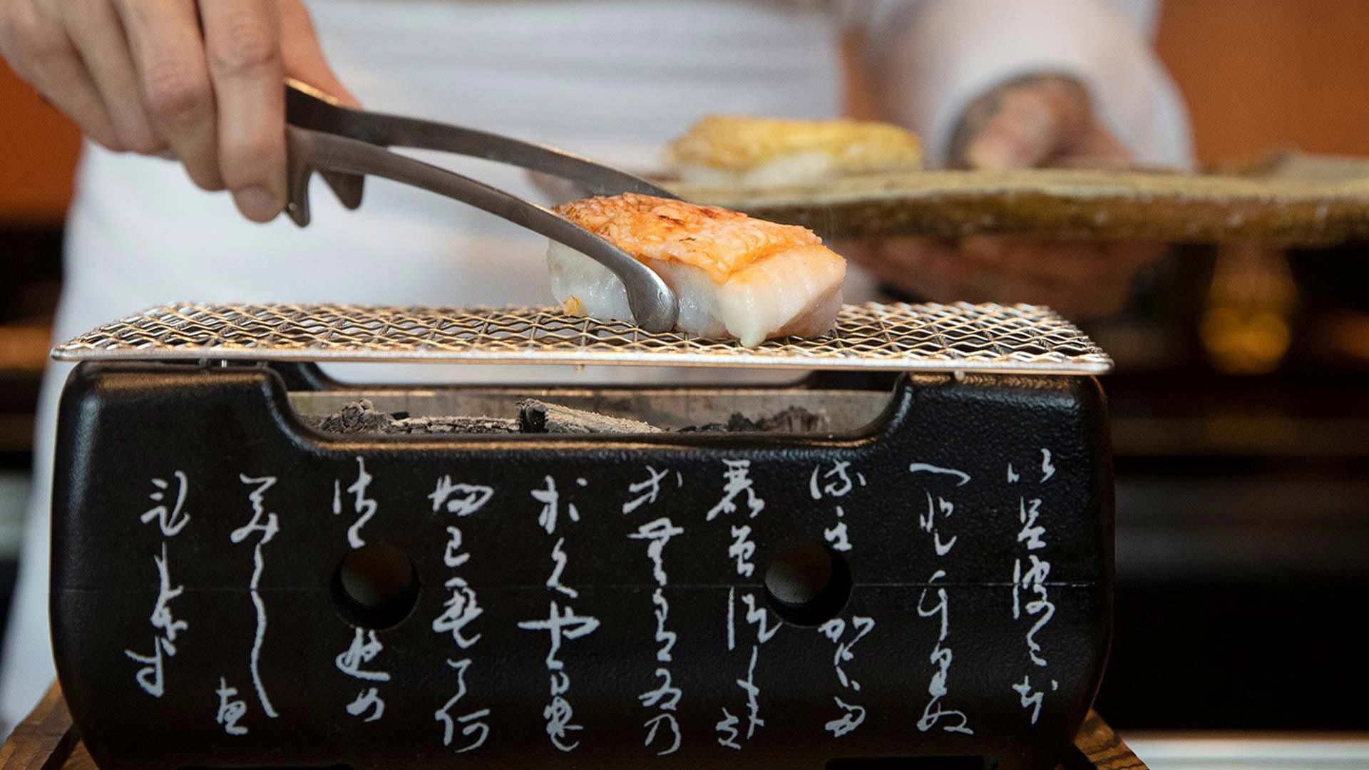 プライベートダイニングイベントに対応可能なレストランWaku Ghinで、魚を炭火で焼いているシェフ