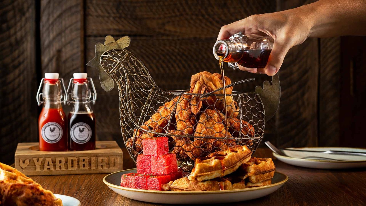 Fried chicken, watermelon and waffles placed in a chicken shaped basket, making it an instagrammable dish at Yardbird